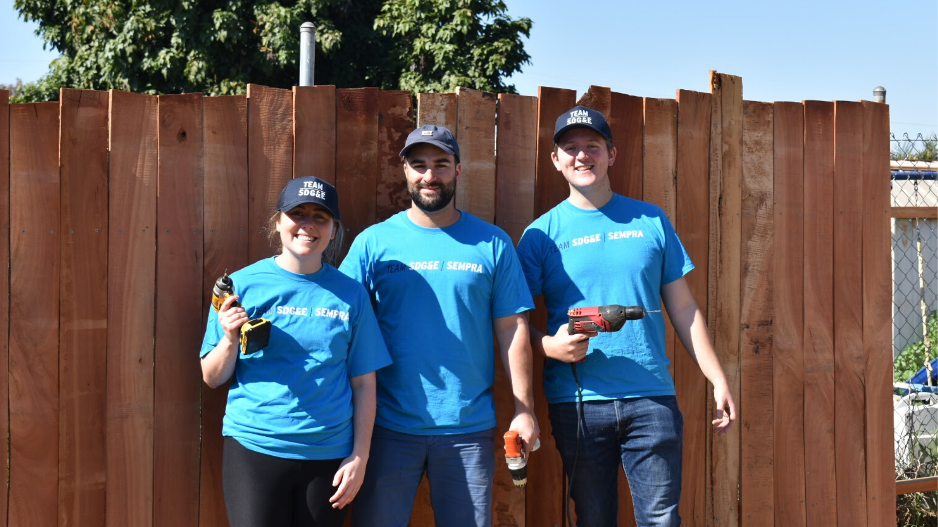 Team SDG&E volunteers pose in front of fence they built at Olivewood Gardens.